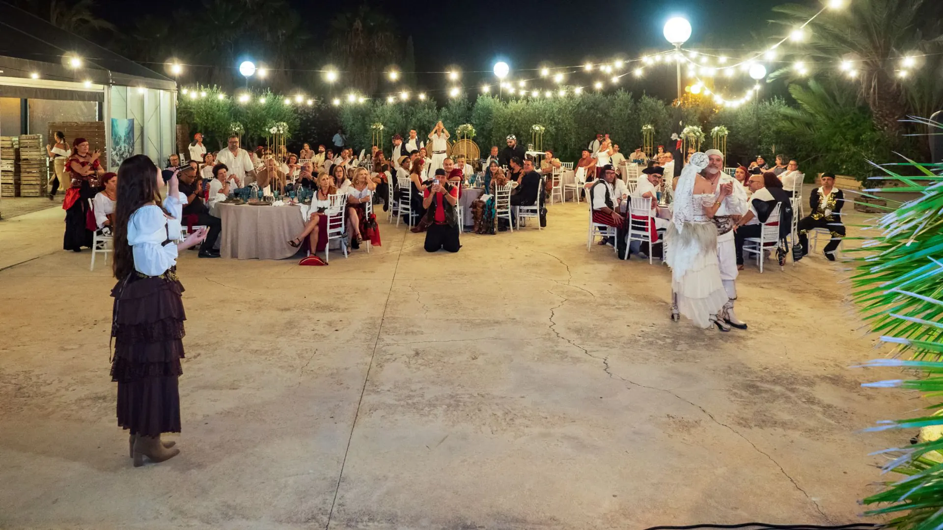 Rocío cantando de noche en una boda al aire libre, con los invitados en sus mesas